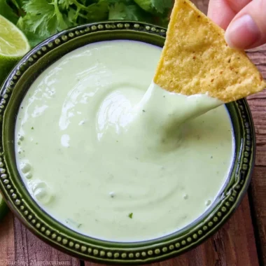 Fresh cilantro lime cream in a bowl with herbs and lime slices
