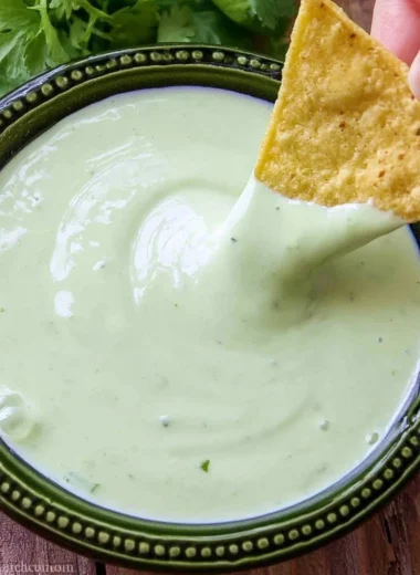 Fresh cilantro lime cream in a bowl with herbs and lime slices