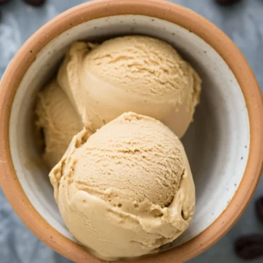 Delicious coffee ice cream served in a cup with coffee beans around it.