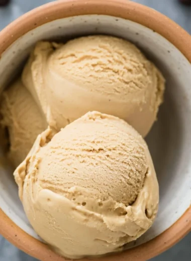 Delicious coffee ice cream served in a cup with coffee beans around it.