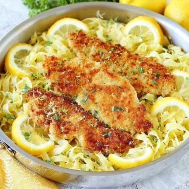 Romano chicken served with lemon garlic pasta on a white plate