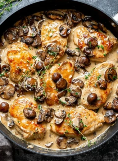 Skillet chicken and mushrooms in a rich wine sauce served on a plate.