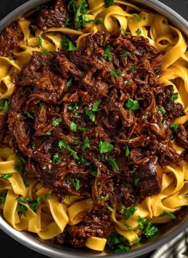 Delicious slow-cooked short rib ragù served over pasta, garnished with herbs.