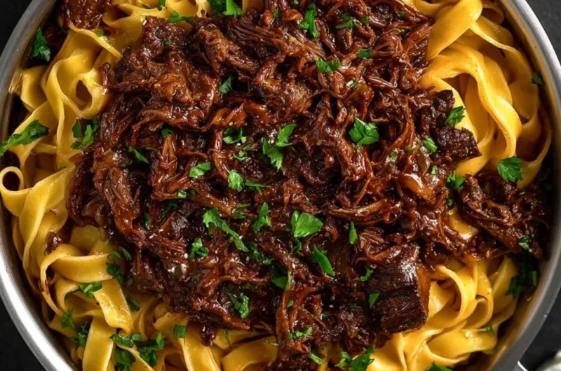 Delicious slow-cooked short rib ragù served over pasta, garnished with herbs.