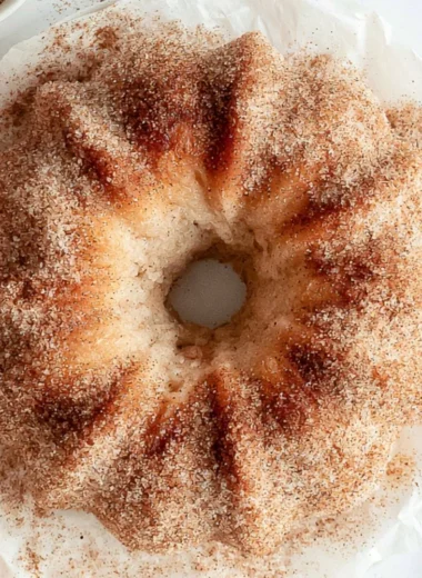 Cozy apple cider donut cake topped with cinnamon glaze and fresh apples