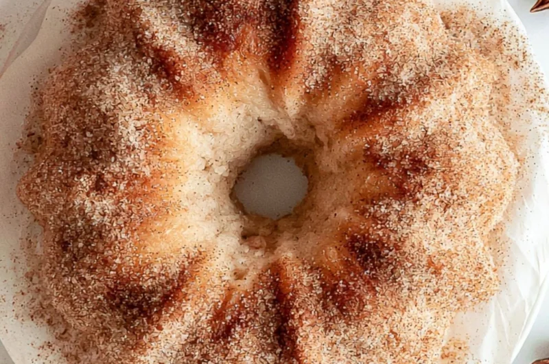 Cozy apple cider donut cake topped with cinnamon glaze and fresh apples