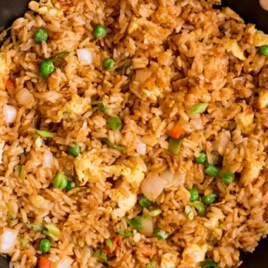 A bowl of Cozy Egg Fried Rice garnished with vegetables and eggs.