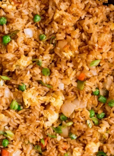 A bowl of Cozy Egg Fried Rice garnished with vegetables and eggs.
