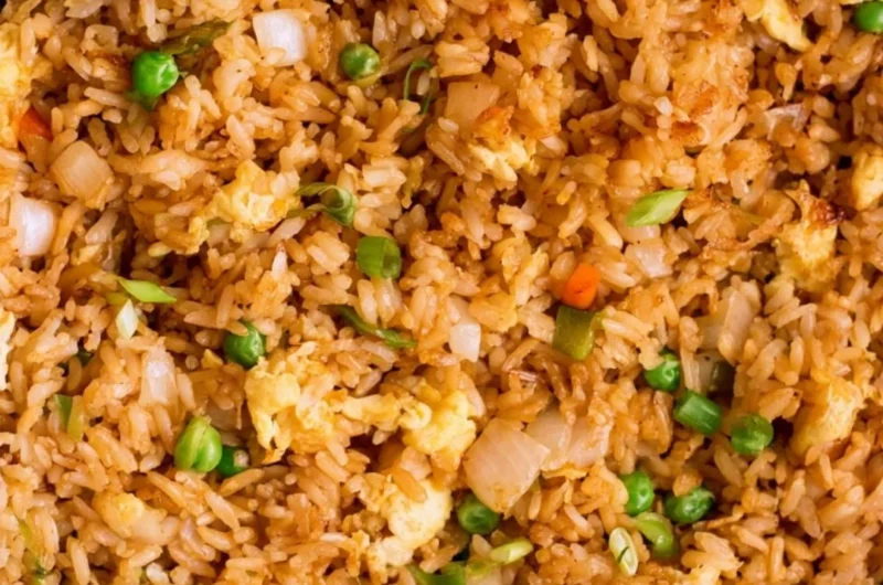 A bowl of Cozy Egg Fried Rice garnished with vegetables and eggs.