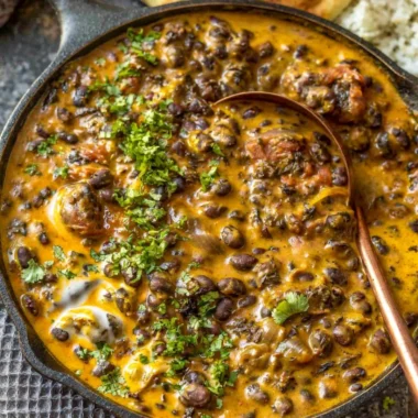 Creamy black bean curry served in a bowl with fresh herbs