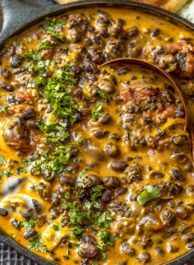 Creamy black bean curry served in a bowl with fresh herbs