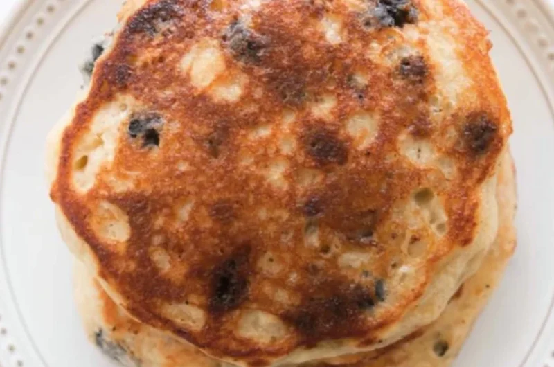 Fluffy sourdough pancakes stacked on a plate with syrup and berries