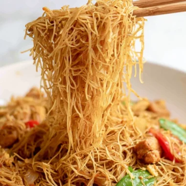 Bowl of Singapore curry noodles served with fresh herbs and vegetables