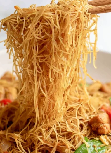 Bowl of Singapore curry noodles served with fresh herbs and vegetables