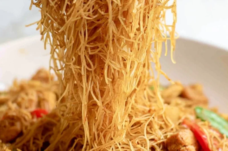 Bowl of Singapore curry noodles served with fresh herbs and vegetables