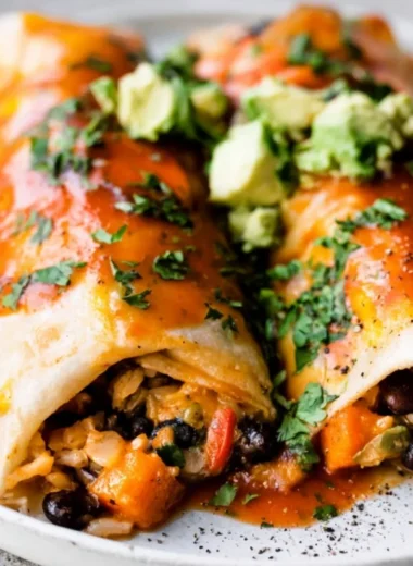 Delicious cozy vegetarian enchiladas served on a plate, garnished with fresh herbs.