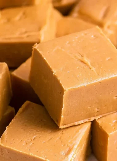 Delicious creamy peanut butter fudge squares on a wooden plate
