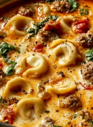 Bowl of Italian Sausage Tortellini Soup garnished with herbs.